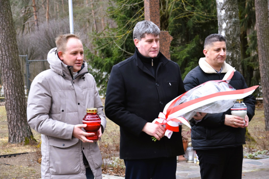 P. Wnukowski (od lewej), P. Rusiecki i T. Choroszewski składają wiązankę kwiatów pod pomnikiem Żołnierzy Armii Krajowej przy kościele Matki Boskiej Częstochowskiej w Augustowie